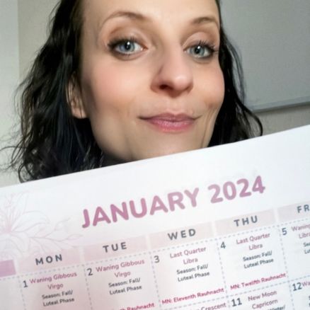 woman smiling into the camera holding and showing a calendar, saying January 2024