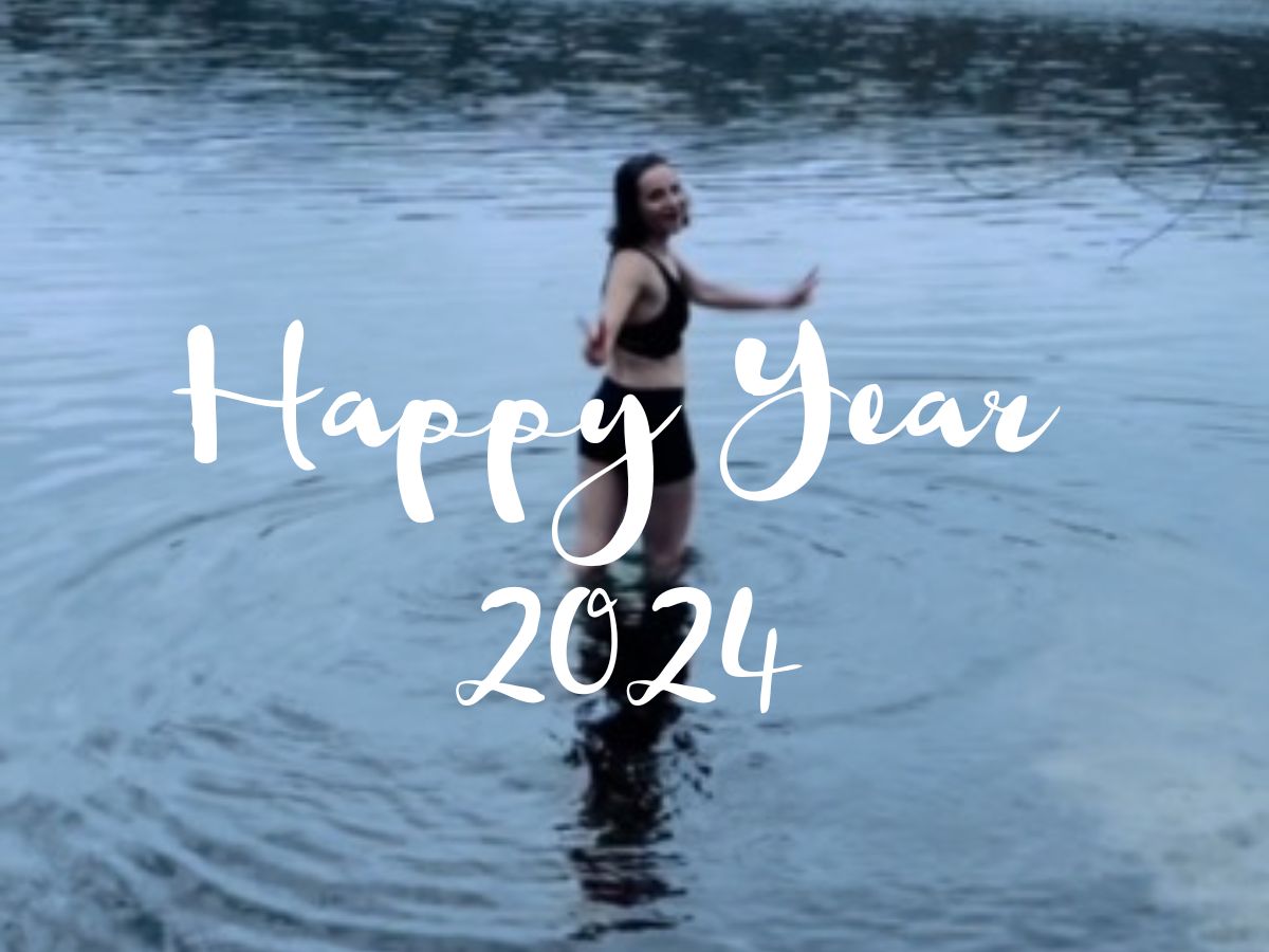 January Review: 2023Woman in the lake, turning to camera and smiling. The headline of the picture is 'Happy Year 2024'