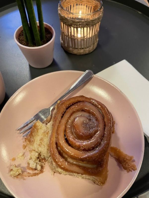 Cinnamon roll on a pink plate in a café.