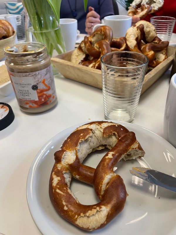 Set table with a pretzel on a plate. In the background, a basket of pretzels.