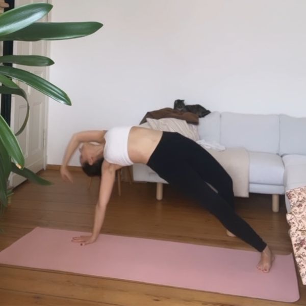 Woman practicing yoga on a pink yoga mat. Yoga pose: Camatkarasana - Wild Thing.