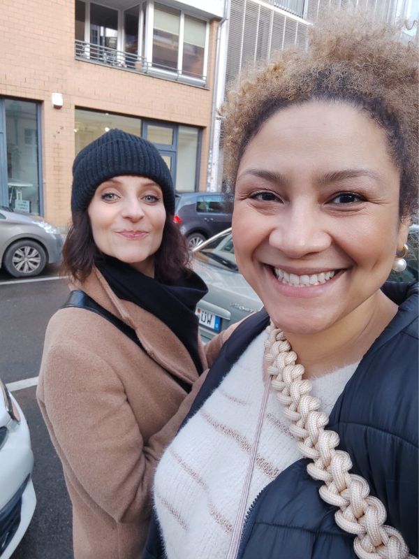 Two women in the streets, taking a selfie and laughing. 