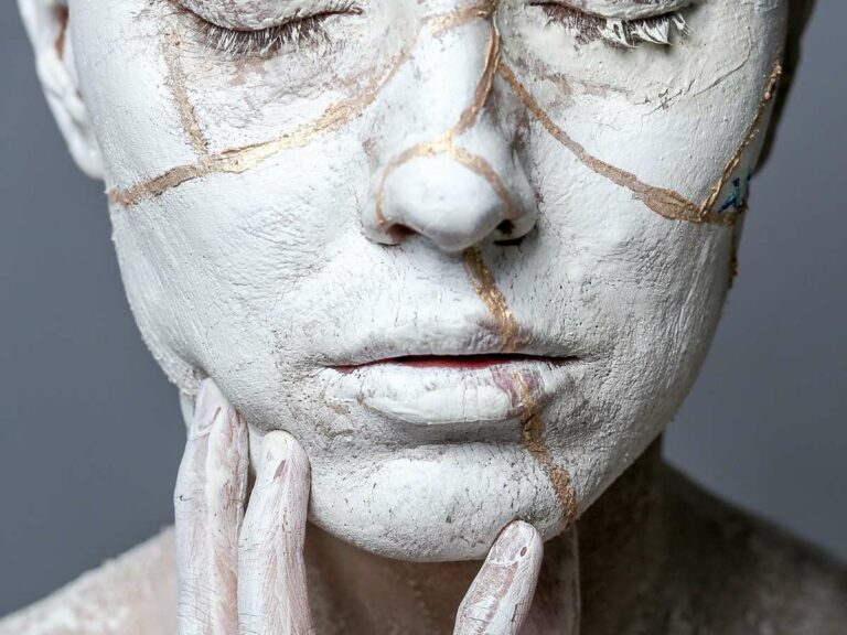 woman's face with white make up and golden stripes