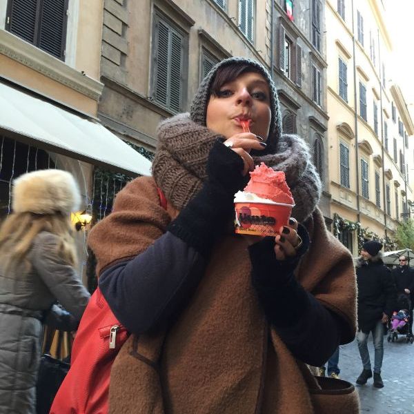 Woman in winter clothes eating ice-cream in Rome