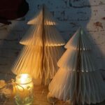 two small white paper christmas trees with a lit candle