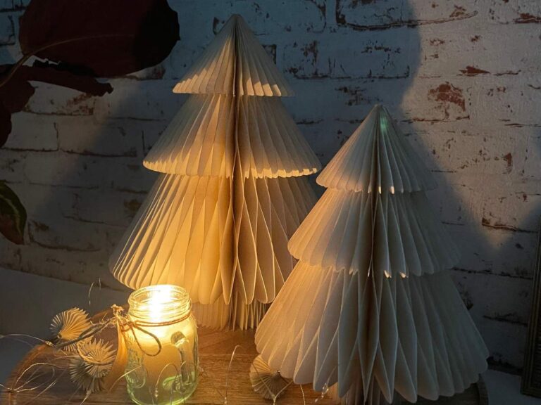 two small white paper christmas trees with a lit candle