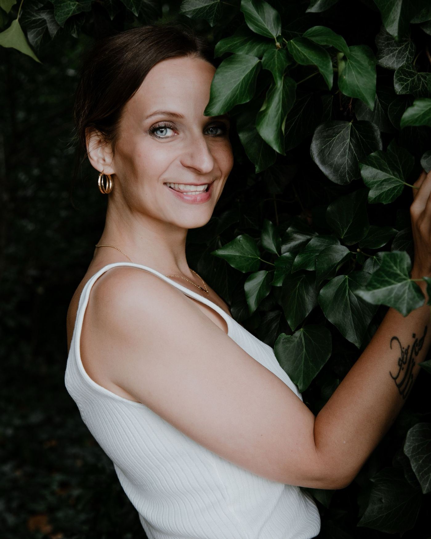 Nadine Kühn smiling in front of an ivy wall