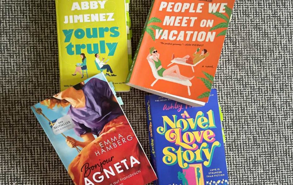 Four books are lying on the floor. The one in bright grean is called Yours truly, the book in orange color is titled People We Meet On Vacation, the book below that one in mostly blue color is titled is titled: A Novel Love Story, the book right next to that one has the title: Bonjour Agneta