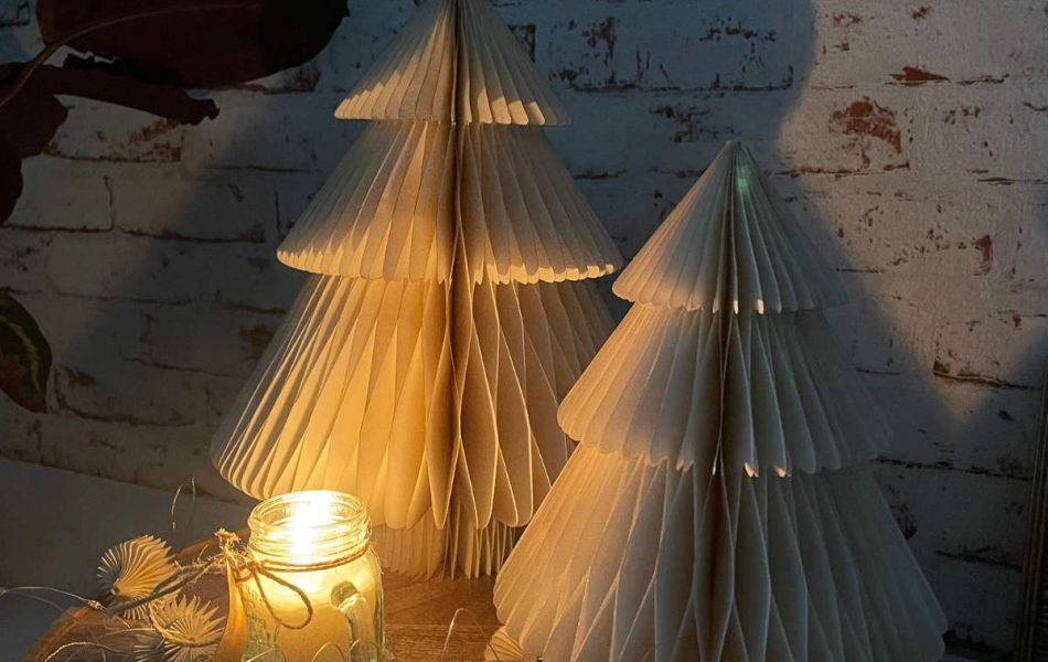 two small white paper christmas trees with a lit candle